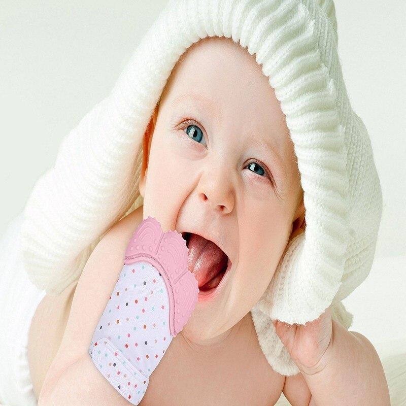 Baby wearing pink and white teething mitten glove with dotted fabric at mouth