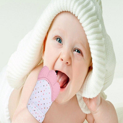 Baby wearing pink and white teething mitten glove with dotted fabric at mouth