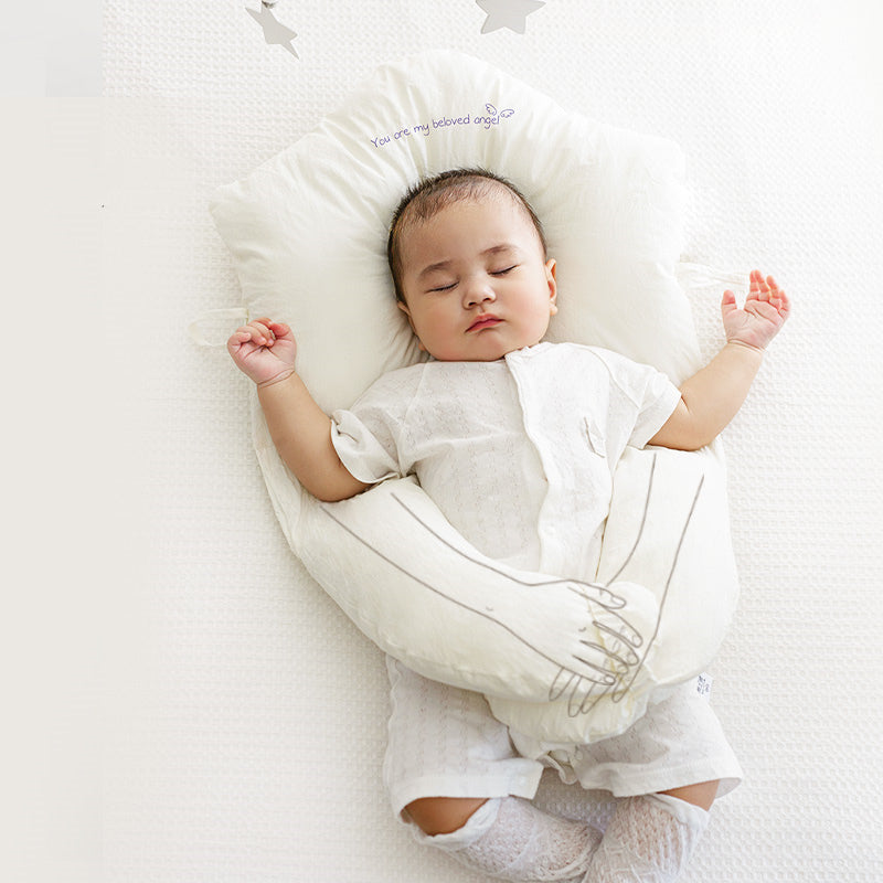 Newborn head shaping pillow, white plush U-shaped support with neck cutout for a sleeping baby