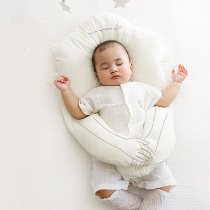 Newborn head shaping pillow, white plush U-shaped support with neck cutout for a sleeping baby