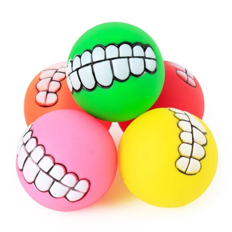Rubber pet teeth squeaky toy balls in green, orange, pink, and yellow, close-up.