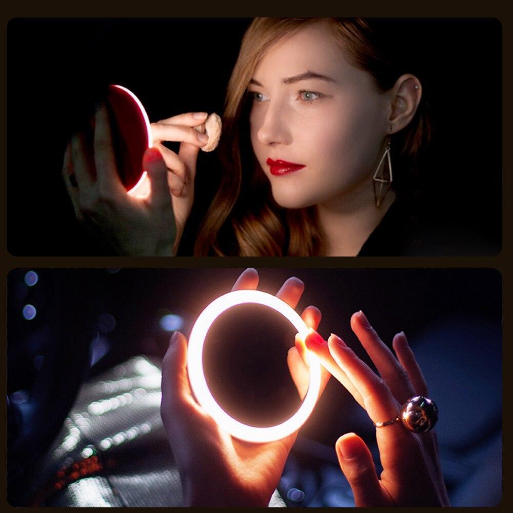 Round LED makeup mirror with glowing ring held near face